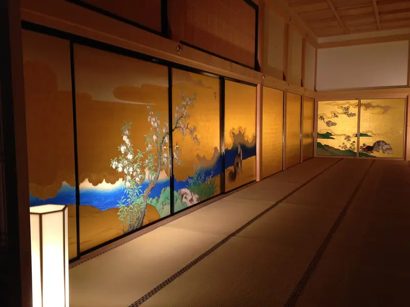 A long tatami room in Honmaru Palace lined with gold sliding doors painted with flowering trees and animals